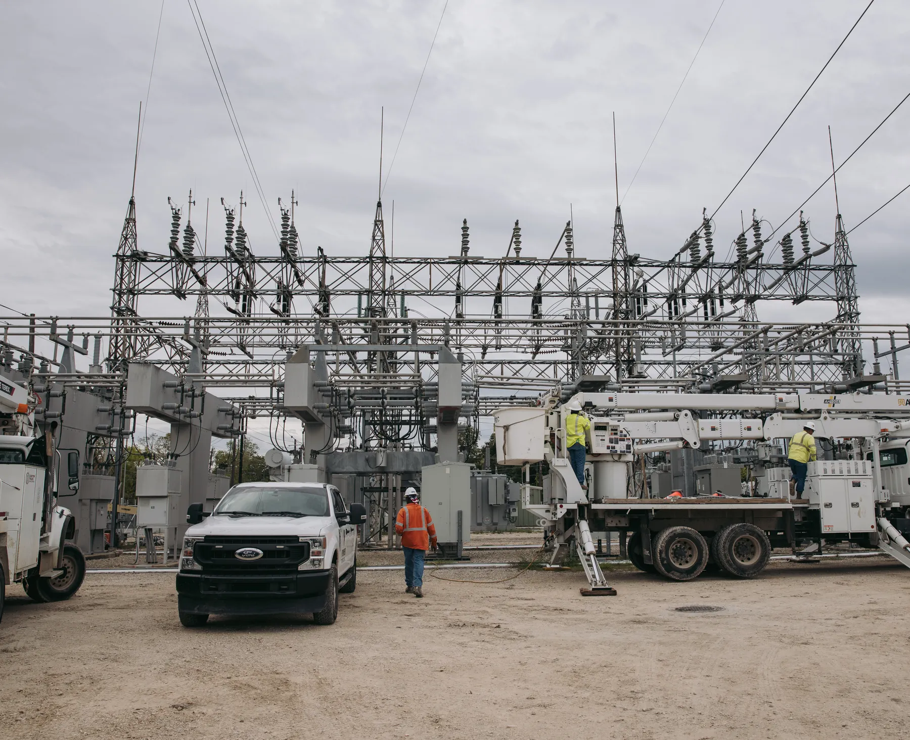 Crew members and bucket trucks at work inside an electrical substation